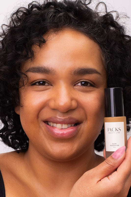 #farbwunsch_n-6, Frau trägt JACKS beauty line Glow Foundation im Gesicht und Flakon in der Hand