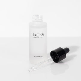 Das JACKS beauty line Beauty Elixir steht offen und der Deckel mit Pipette liegt vor der Glasflasche