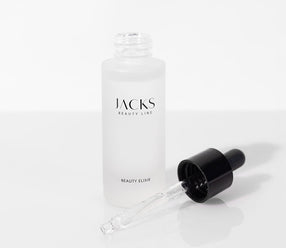Das JACKS beauty line Beauty Elixir steht offen und der Deckel mit Pipette liegt vor der Glasflasche