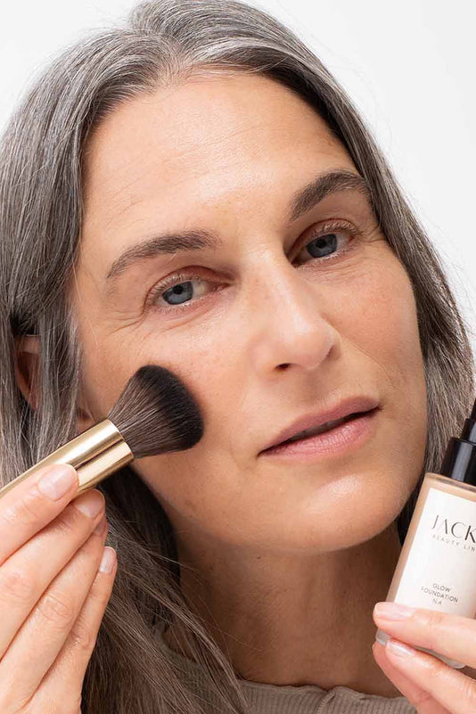 Frau trägt die JACKS beauty line Glow Foundation mit dem #12 Foundationpinsel auf