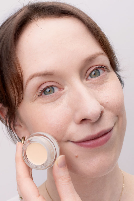 #farbwunsch_n-1, Frau trägt Cover Concealer Farbe N.1 und hält Concealer Tiegel in der Hand