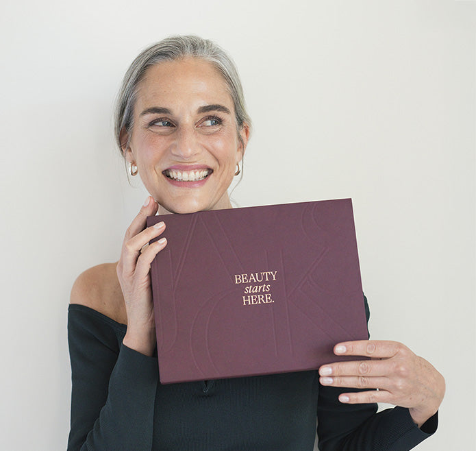 Frau hält den dunkelroten JACKS beauty line Adventskalender 2025 in den Händen