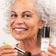 #farbwunsch_n-5, Frau Ü50 hält die JACKS beauty line Glow Foundation N.5 und den Mini Foundationpinsel