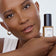 #farbwunsch_n-7, Schwarze Frau hält JACKS beauty line Cover Foundation N7 Flakon neben ihrem Gesicht