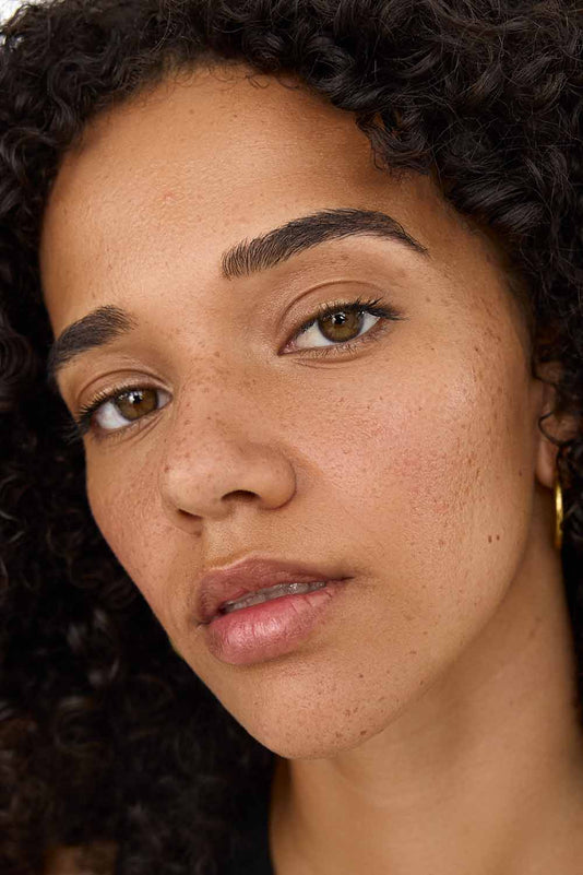 #farbwunsch_n-6, Frau mit braunen Haaren hält den JACKS beauty line Cream Concealer N6 neben ihr Gesicht