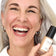 #farbwunsch_n-3, #farbwunsch_mittlerer-bis-dunkler-hauttyp, Frau trägt JACKS beauty line Glow Foundation N4 im Gesicht und Flakon in der Hand