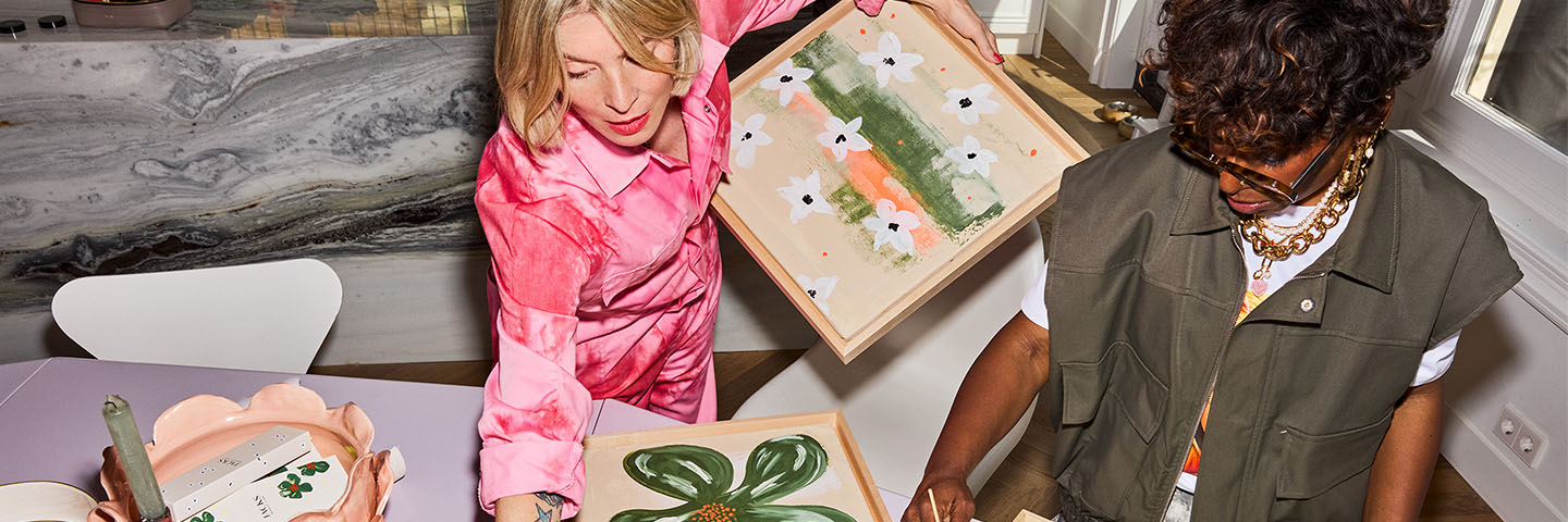 Denise Boomkens mit ihrer Assistentin in ihrer Wohnung mit bunt bemalten Leinwänden