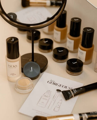 Viele JACKS beauty line Make-up Produkte wie Foundation, Concealer und Pinsel liegen auf einem Tisch