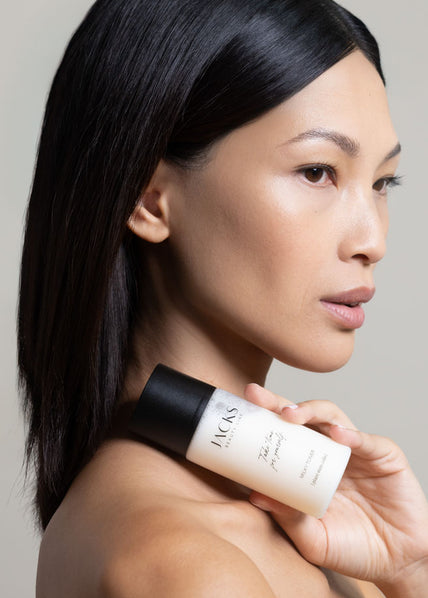 Eine Frau hält den JACKS beauty line Milky Toner vor ihrem Schlüsselbein