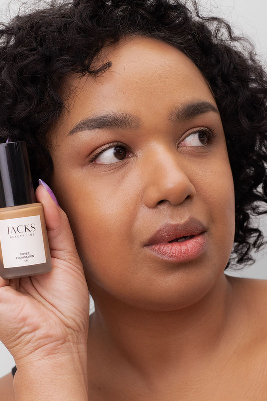 #farbwunsch_n-6, Frau mit JACKS beauty line Cover Foundation Farbe N6 im Gesicht und Flakon in der Hand 