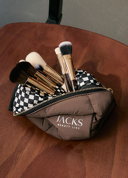 JACKS Make-up Pinsel schauen aus einer braunen Kosmetiktasche raus